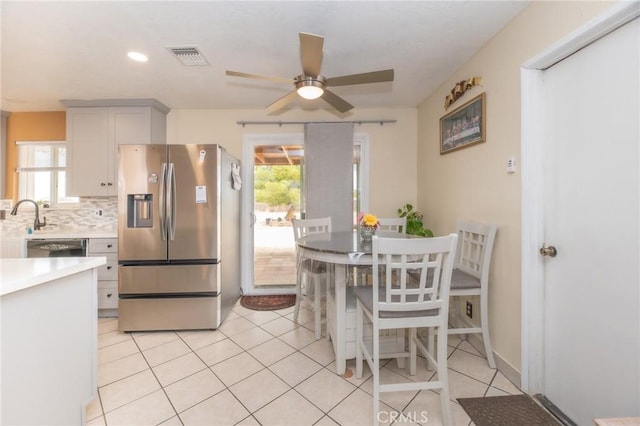 kitchen featuring light countertops, a healthy amount of sunlight, stainless steel fridge, and backsplash