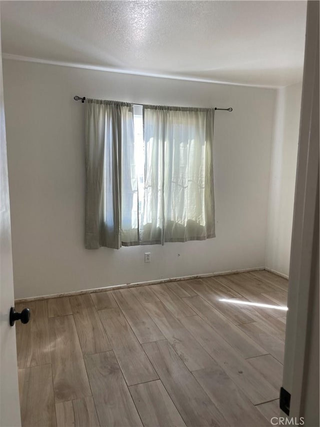 unfurnished room with a textured ceiling and wood finished floors