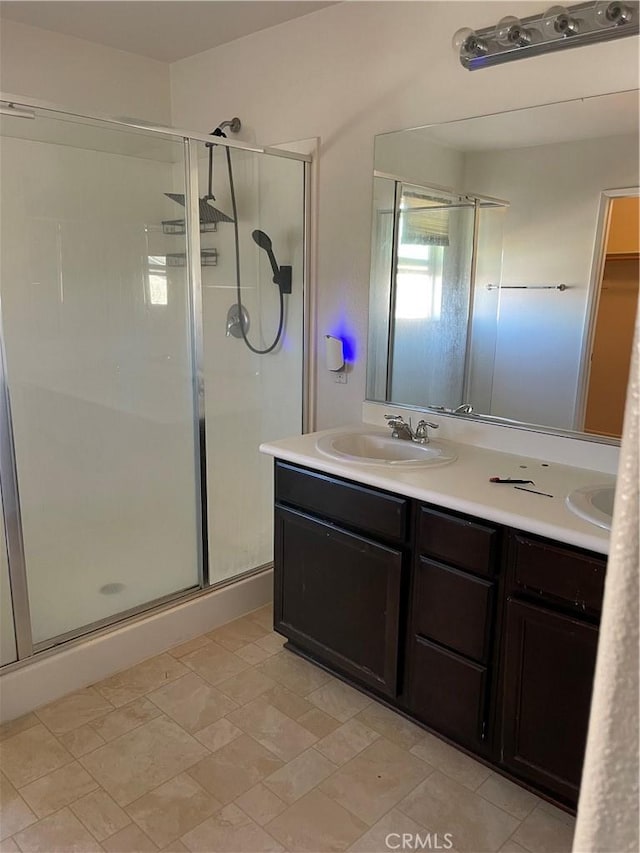 full bathroom with double vanity, a stall shower, and a sink