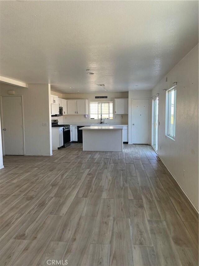 kitchen with light wood finished floors, open floor plan, gas range, and white cabinets