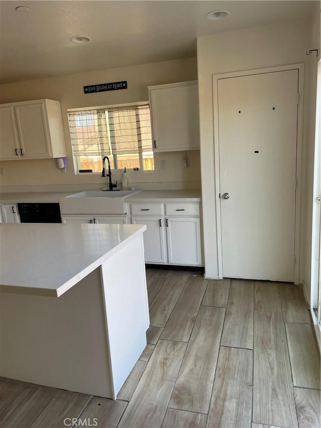 kitchen featuring white cabinets, light countertops, light wood-type flooring, and a sink