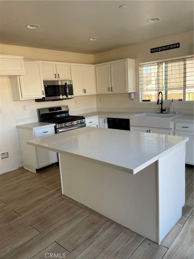 kitchen with a sink, light wood-style floors, white cabinetry, and stainless steel appliances