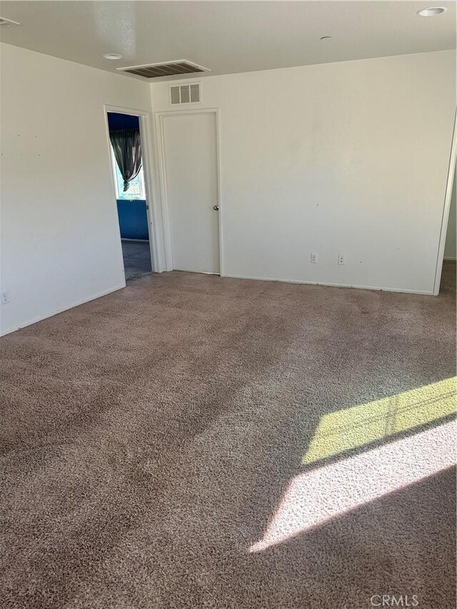 unfurnished room featuring visible vents and carpet