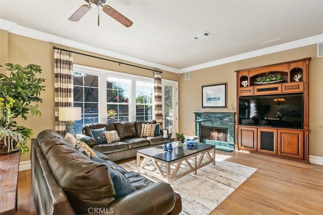 living area with visible vents, a ceiling fan, light wood-style flooring, and crown molding