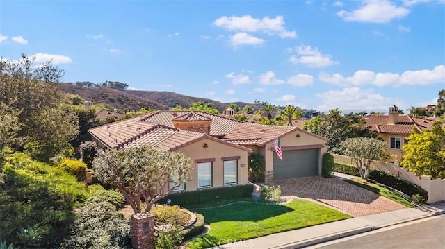 mediterranean / spanish house with stucco siding, driveway, a tile roof, a front yard, and a garage