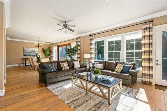 living room featuring ornamental molding, ceiling fan with notable chandelier, baseboards, and hardwood / wood-style flooring