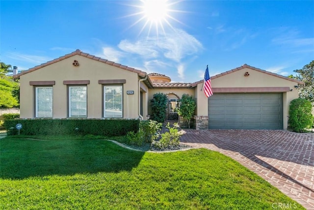 mediterranean / spanish-style home with stucco siding, driveway, a front lawn, a tile roof, and a garage