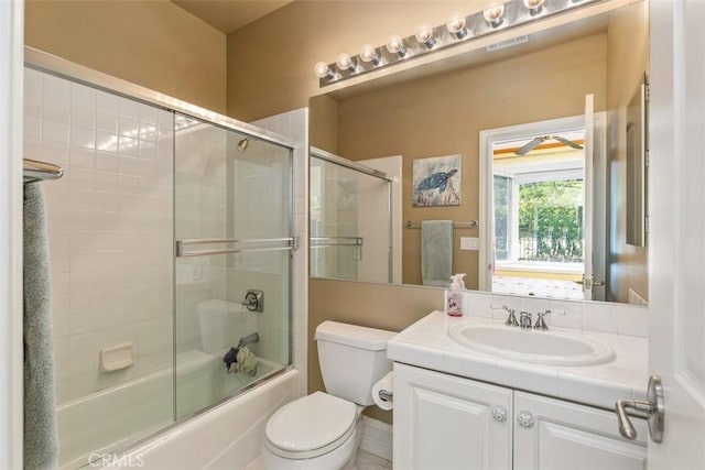 full bathroom with visible vents, toilet, vanity, and shower / bath combination with glass door