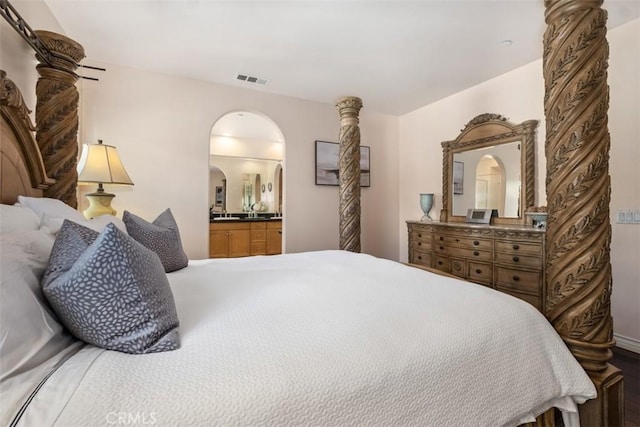 bedroom featuring ensuite bath and arched walkways