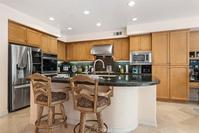 kitchen with under cabinet range hood, visible vents, stainless steel appliances, and brown cabinetry