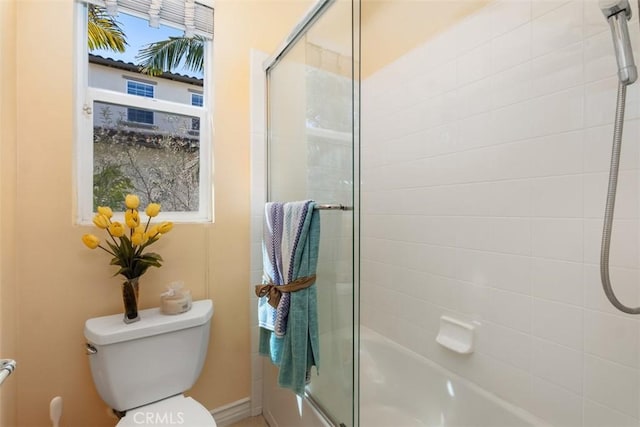 bathroom featuring combined bath / shower with glass door and toilet