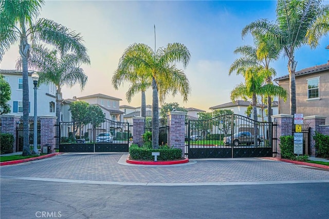 view of street featuring curbs, street lights, a gated entry, and a gate