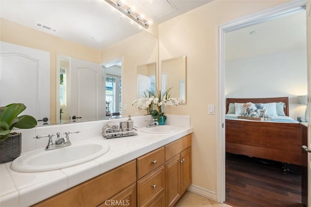 ensuite bathroom with double vanity, visible vents, connected bathroom, and a sink