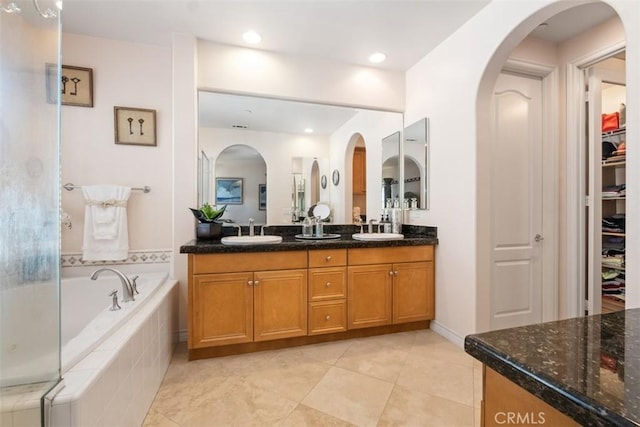 full bath with tile patterned flooring, double vanity, a bath, and a sink