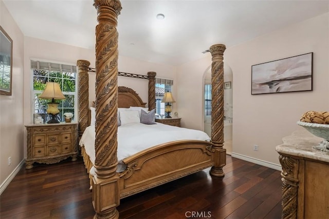 bedroom featuring baseboards, wood-type flooring, and arched walkways