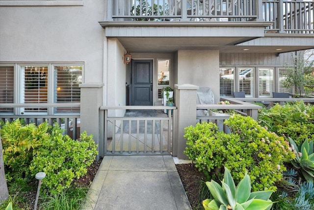 doorway to property featuring stucco siding, a balcony, and brick siding