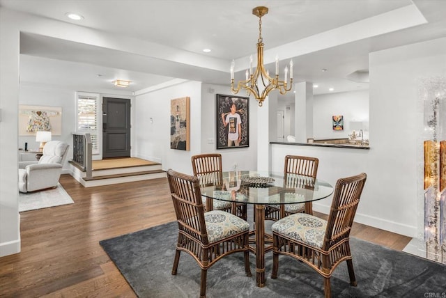 dining room featuring recessed lighting, baseboards, a raised ceiling, and wood finished floors