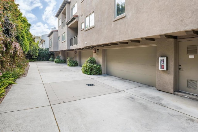 exterior space featuring a garage, driveway, and stucco siding