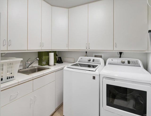 laundry room with washing machine and clothes dryer, cabinet space, and a sink