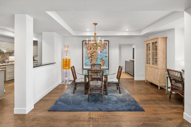 dining room with a raised ceiling, recessed lighting, wood finished floors, and baseboards