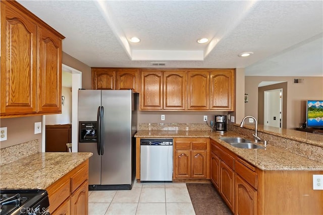 kitchen featuring brown cabinets, appliances with stainless steel finishes, a raised ceiling, and a sink