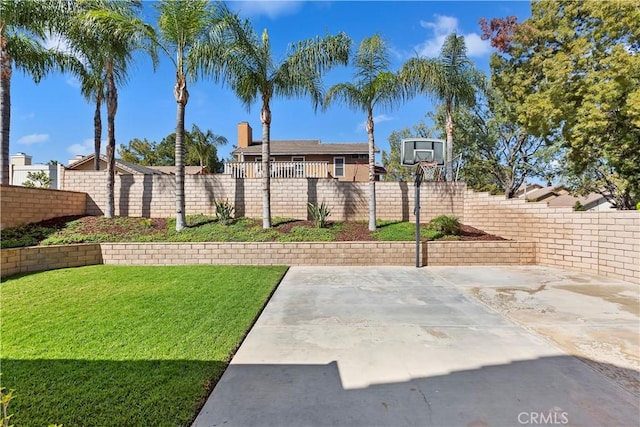 view of basketball court featuring a lawn and a fenced backyard