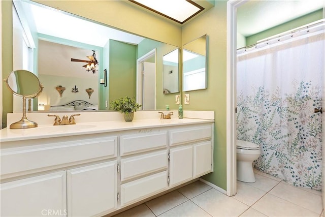 full bathroom with double vanity, ceiling fan, a sink, tile patterned floors, and toilet