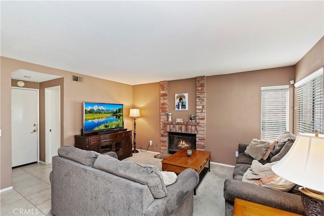 living room featuring light tile patterned floors, visible vents, baseboards, and a brick fireplace