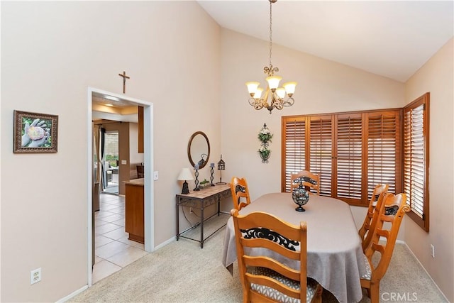 dining area featuring light colored carpet, baseboards, a chandelier, and high vaulted ceiling