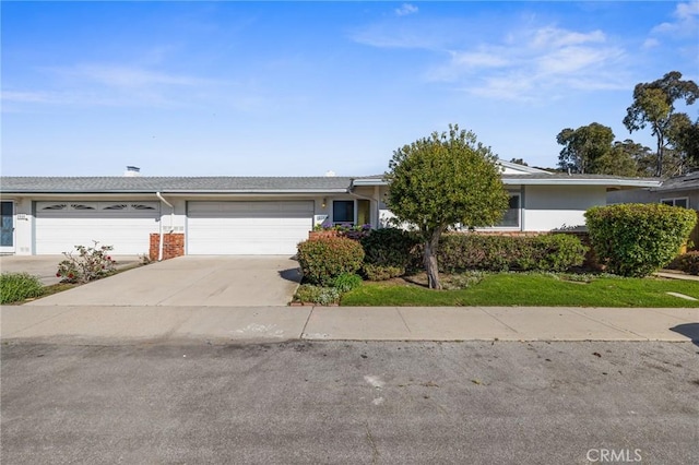 ranch-style house featuring stucco siding, driveway, brick siding, and an attached garage