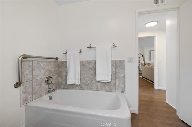 full bath with a bath, wood finished floors, visible vents, and baseboards