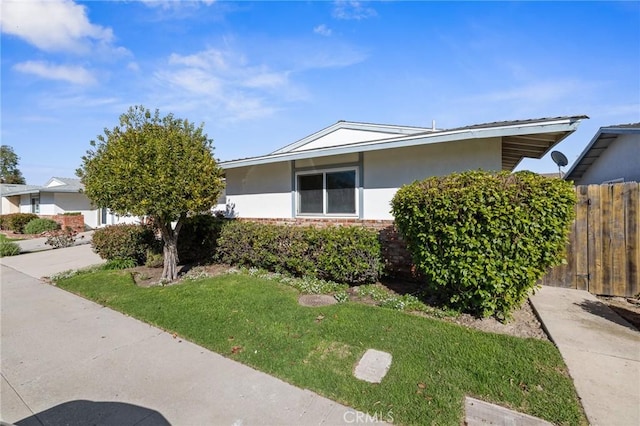 view of front of home with fence, brick siding, driveway, and stucco siding