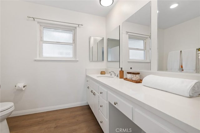 bathroom featuring vanity, toilet, wood finished floors, and baseboards