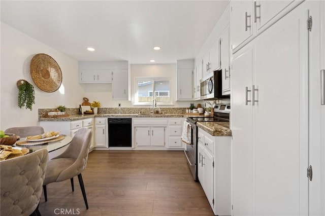 kitchen featuring a sink, white cabinets, wood finished floors, and stainless steel appliances