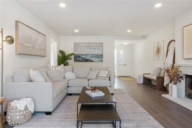 living area with recessed lighting, a fireplace, and light wood-style floors