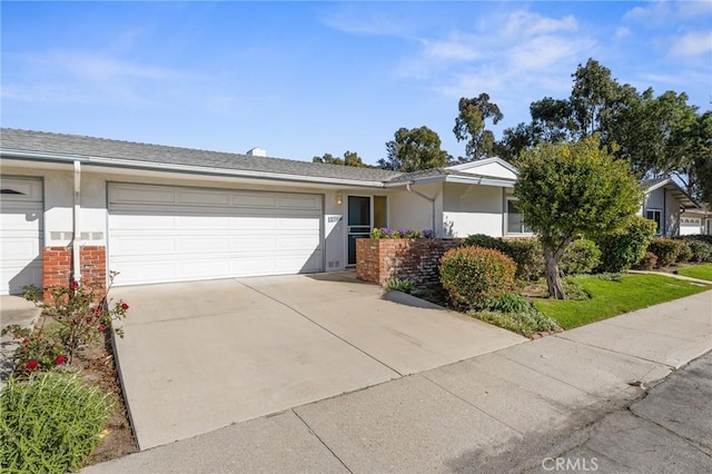 single story home featuring concrete driveway, an attached garage, brick siding, and stucco siding