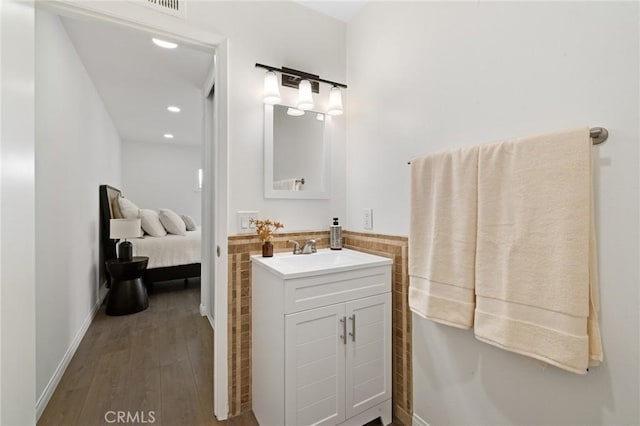 bathroom with baseboards, vanity, recessed lighting, wood finished floors, and ensuite bath