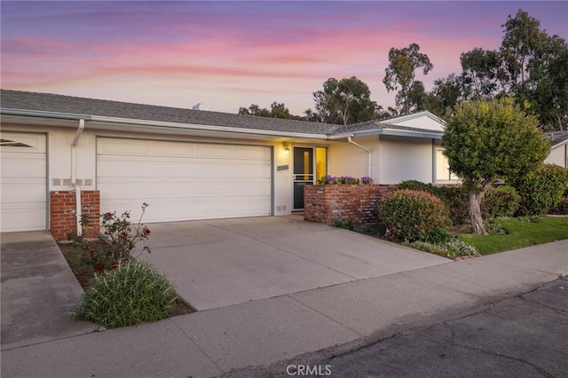 ranch-style house featuring stucco siding, brick siding, concrete driveway, and an attached garage