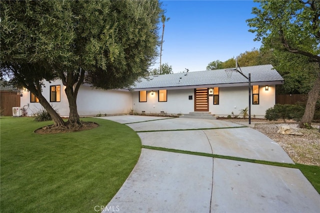 rear view of property with concrete driveway, fence, a lawn, and crawl space