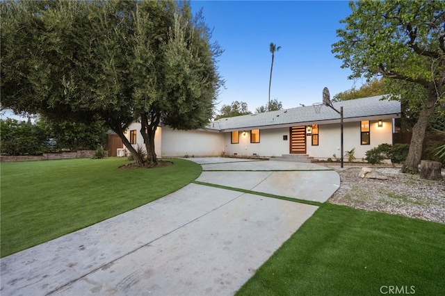 rear view of house featuring a lawn and driveway