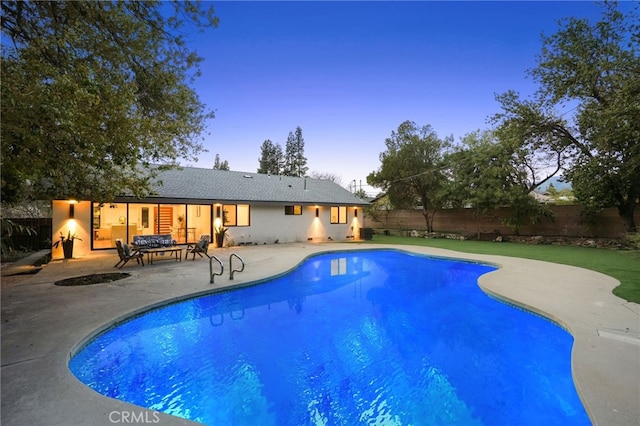 pool at dusk featuring a fenced in pool, a fenced backyard, and a patio area