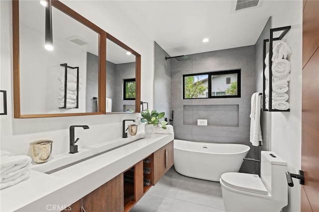 bathroom featuring visible vents, vanity, a freestanding bath, and tile walls