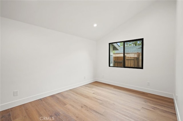 spare room featuring recessed lighting, light wood-style flooring, baseboards, and vaulted ceiling