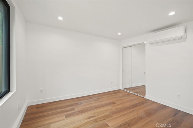 empty room with recessed lighting, an AC wall unit, and light wood-type flooring