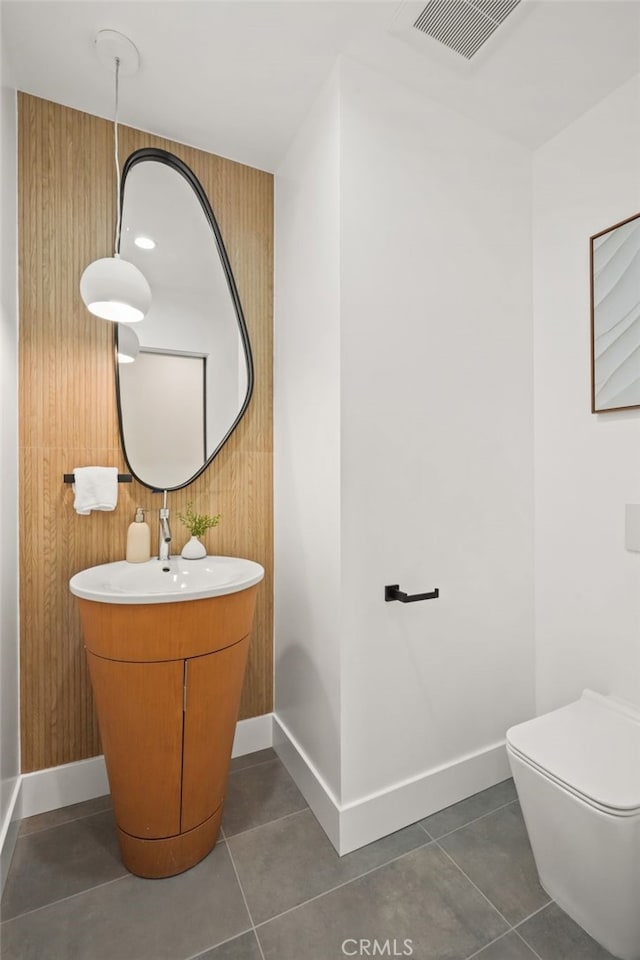 half bath with tile patterned flooring, toilet, baseboards, and visible vents