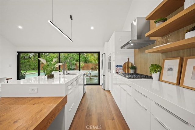 kitchen featuring white cabinetry, modern cabinets, wall chimney range hood, and a sink