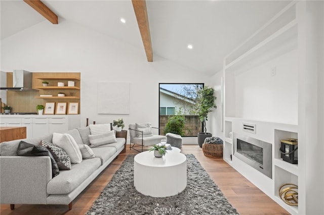 living area with beamed ceiling, high vaulted ceiling, a glass covered fireplace, wood finished floors, and recessed lighting