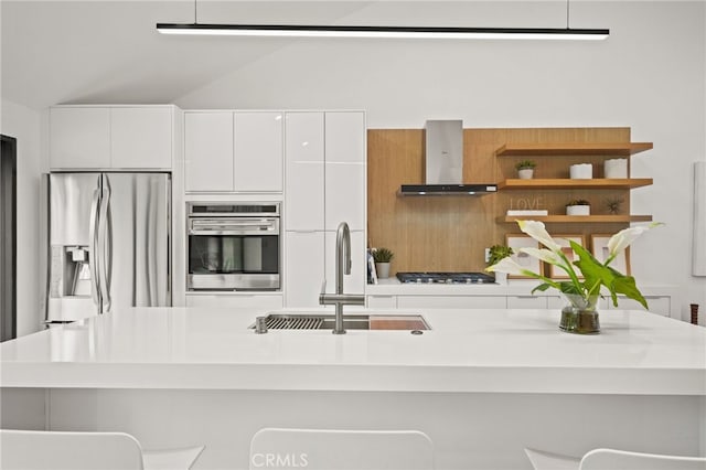 kitchen featuring a sink, wall chimney range hood, stainless steel appliances, white cabinetry, and modern cabinets