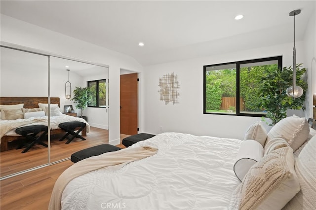 bedroom with a closet, recessed lighting, lofted ceiling, and wood finished floors