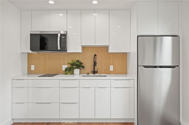 kitchen featuring modern cabinets, a sink, stainless steel appliances, white cabinets, and light countertops